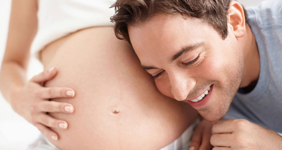 A man is embracing a pregnant woman.